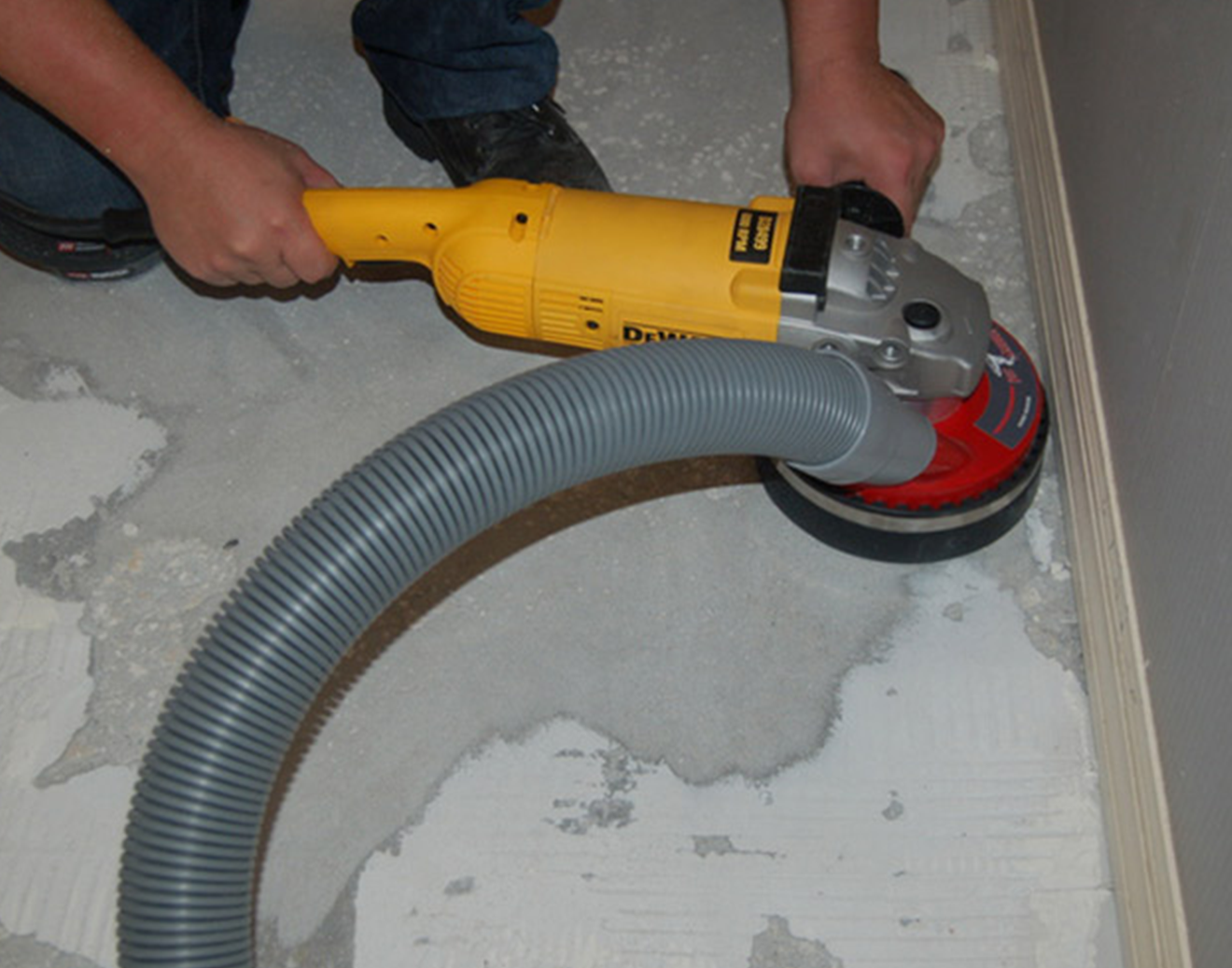 Angle grinder fitted with a dust shroud and extraction hose